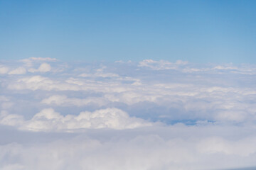 Airplane jet flying above clouds view with blue sky from the window in traveling and transportation concept. Nature landscape background.