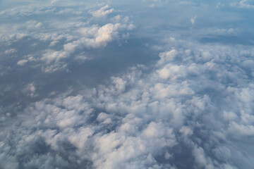 Airplane jet flying above clouds view with blue sky from the window in traveling and transportation concept. Nature landscape background.
