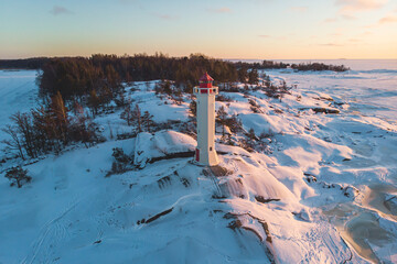 Snowy aerial drone view of Povorotny lighthouse, Vikhrevoi island, Gulf of Finland, Vyborg bay, Leningrad oblast, Russia, winter sunny day with a blue sky, lighthouses of Russia travel