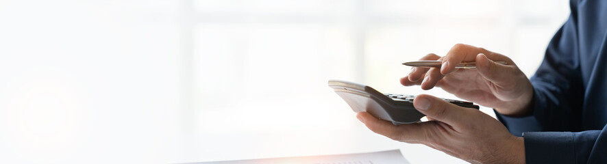 copy space of young businessman accounting analyzing using calculator to calculate and check revenue database marketing expenses By pointing to graphs, charts to compare real estate business data.