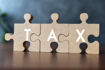 Taxes concept with wooden puzzle on a desk. Jigsaw puzzle as the task of putting together a...