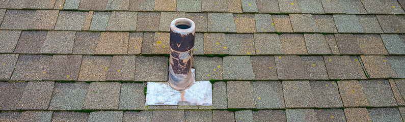Closeup of roof vent on a weathered asphalt shingle roof
