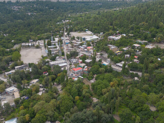 Fototapeta na wymiar Aerial top view of Muree village, Islamabad with residential local houses and fog mist, nature trees, Pakistan in urban city town in Asia, buildings.