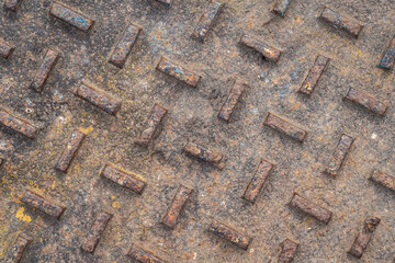 Close up photograph of an old vintage steel manhole cover with extremely weathered rusted and pitted diamond plate relief pattern making a great industrial background.