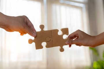 Business concept. Close up of hands connecting two pieces of jigsaw puzzle over the beautiful sunset