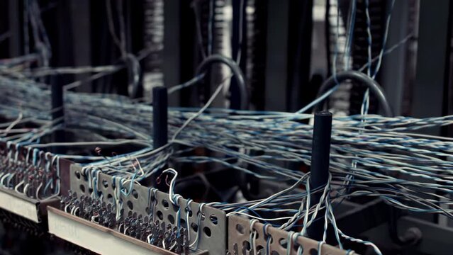 Vintage telephone exchange station, featuring connection wires and a classic red telephone. Witness the mechanics of early telecommunications technology as copper wires