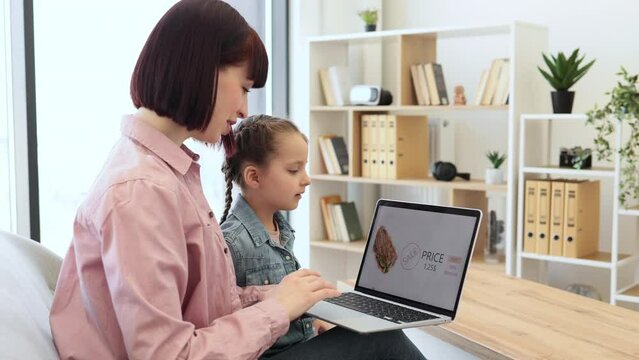 Dark haired woman and little girl using portable laptop for ordering lunch in online shop. Happy mother with lovely daughter purchasing food with discount for saving and free time at home.