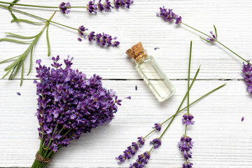 Obraz na płótnie Canvas Bouquet of lavender flowers and lavender oil on a white wooden background.