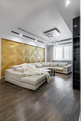 Living room with white walls and a huge white sofa, a black glossy wardrobe with a large yellow 3D panel on the wall