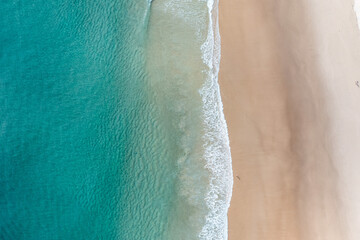 Aerial view of a beach with stunning clear water and warm white sand in a holiday paradise near the Pacific Ocean