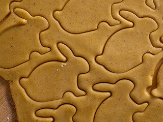 Close-up kneaded ginger dough and carved figurines from it. The shapes of rabbit. Cutting sugar cookie dough with Easter shaped cookie cutters. Preparation for Easter. Holidays baking.