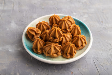 Homemade soft caramel fudge candies on gray concrete, side view, close up.