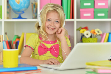 girl in headphones ding with laptop sitting at desk