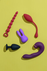 Top view of adult sex toys such as dildo, vibrator, buttplug on yellow background. Sex shop concept