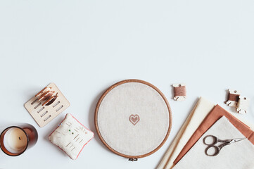 cross stitch embroidery accessories. Linen cloth in hoop on white background with floss, scissors...