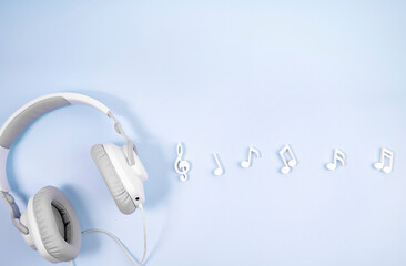 Headphones with notes on a blue background. The concept of listening to music.