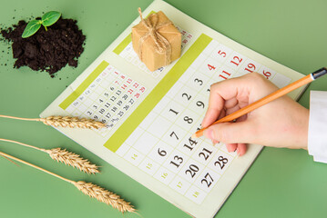 A woman's hand circles the date on the calendar. April 14 is Earth Day. The concept of caring for the environment
