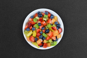 Bowl of colorful fresh fruit on dark background