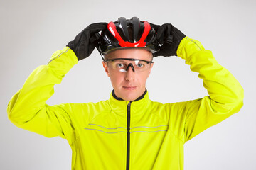 Cycling Concepts. Portrait of Professional Cyclist Posing Equipped in Green Jacket With Glasses and Helmet Against White.