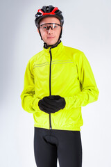 Cycling Concepts. Portrait of Professional Cyclist Posing Equipped in Green Jacket With Glasses and Helmet Against White.