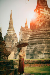 asian woman holding bamboo umbrella standing against stupa in ancient temple of ayutthaya world heritage site of unesco central of thailand - obrazy, fototapety, plakaty