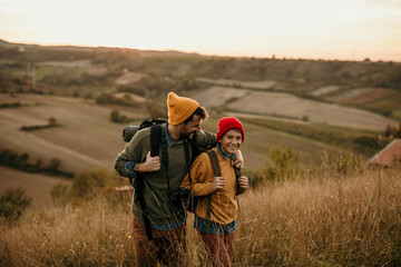 Image of a young father walking and talking with his teenage son in an autumn field, exploring and...