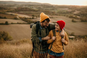 Close up image of a mid adult father walking and talking with his teenage son in an autumn field,...
