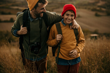 Close up image of a mid adult father walking and talking with his teenage son in an autumn field,...