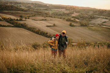 A mid adult father walking and talking with his teenage son in an autumn field, exploring and having fun.