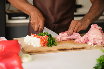 Unrecognizable young african man de-boning chicken to prepare a recipe.