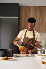 Fototapeta na wymiar Young black man serving tomato sauce on fried chicken mince and rice on a plate.