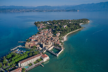 Aerial view of Sirmione, an ancient village on southern Garda Lake. Scaligero Castle drone view. Italian castles Scaligero on the water.  Popular travel destination on Lake Garda in Italy. - obrazy, fototapety, plakaty