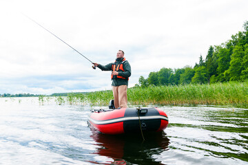 A fisherman throws a fishing rod into the water. Fishing by spinning from a boat
