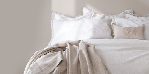 Close up of bed with lacework cover sheet, white and brown embroidered pillowcase and cushion in morning sunlight from window on beige wall bedroom for vintage style interior decoration background 3D