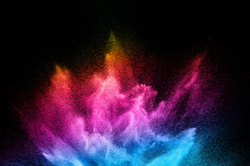 Multi colour powder explosion on black background. Launched colourful dust  particles splashing.