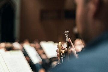 A musician holding their trumpet during a classical symphony orchestra rehearsal