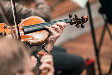 A musician playing the violin in a string section of a classical symphony orchestra rehearsal