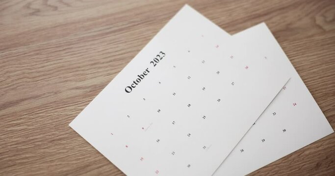 Woman hand puts sheets of calendar with months for 2023 on table