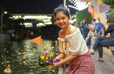 Portrait of Asian Thai woman with Loy Krathong in Thailand , floating on water in local street...