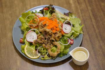 top view salad and caviar with fried calamari in a ceramic plate and mayonnaise sauce on wooden table background, food, nature, health, copy space