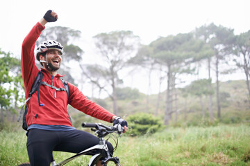 Fototapeta Pure exhilaration. A young male athlete pumping his fist in the air after conquering a mountain biking trail. obraz