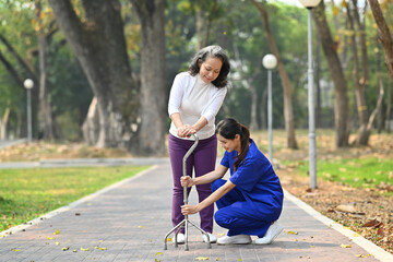 Attentive female caregiver helping, teaching senior woman to walking with walker. Assistance, rehabilitation and health