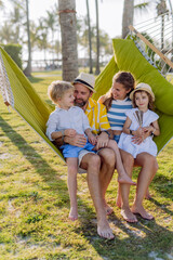 Young family with little kids enjoying their holiday in exotic country, lying in hammock.
