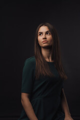 Portrait of young woman in studio, black background.