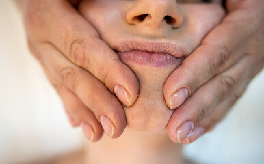 masseuse with working hands massages the face of a female client in a spa salon.