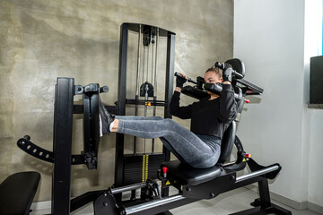 Attractive young woman doing exercises with a machine in the gym.