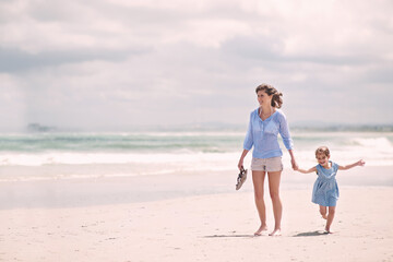 Taking a stroll on the beach. young mother and her daughter going for a walk along the beach.