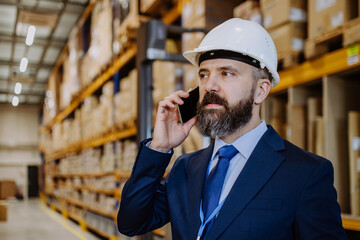 Manager woman in suit calling in a waehouse.