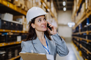 Manager woman in suit calling in a waehouse.