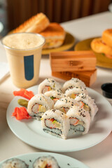 Fresh sushi maki with wasabi and ginger in wooden table with drinks